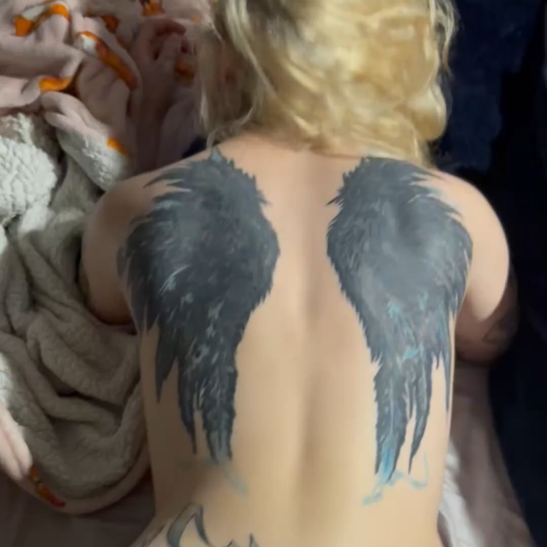blonde with wings tattooed on her back on her knees getting fucked